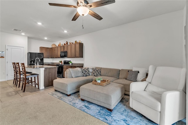 tiled living room with ceiling fan and sink