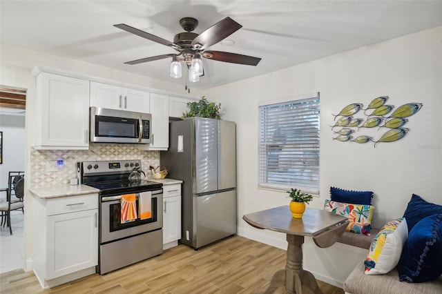 kitchen with tasteful backsplash, white cabinetry, stainless steel appliances, and light wood-type flooring