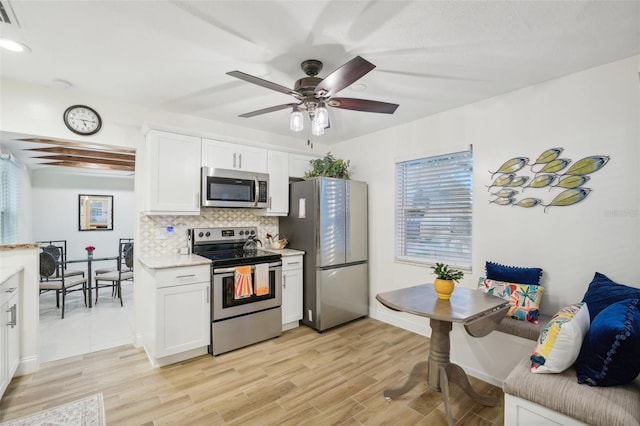 kitchen featuring light wood-type flooring, stainless steel appliances, white cabinetry, and tasteful backsplash