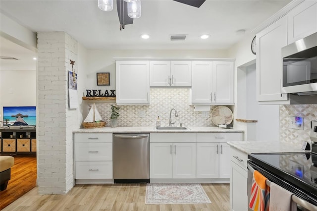 kitchen with white cabinetry, sink, light hardwood / wood-style floors, and appliances with stainless steel finishes