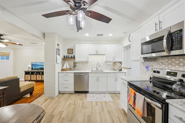 kitchen featuring tasteful backsplash, white cabinetry, light hardwood / wood-style flooring, and appliances with stainless steel finishes