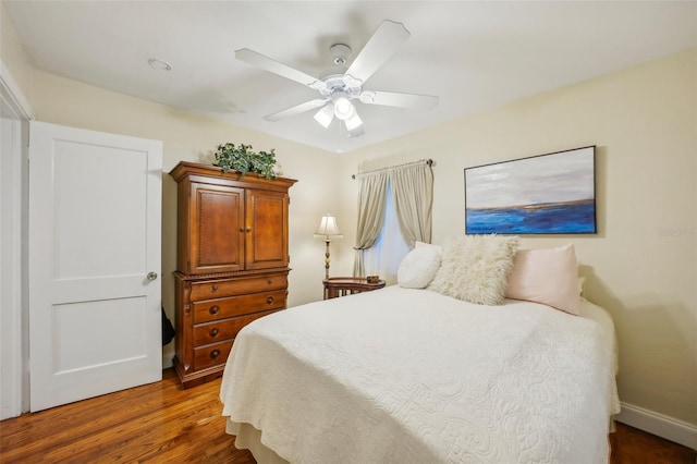 bedroom with dark hardwood / wood-style flooring and ceiling fan