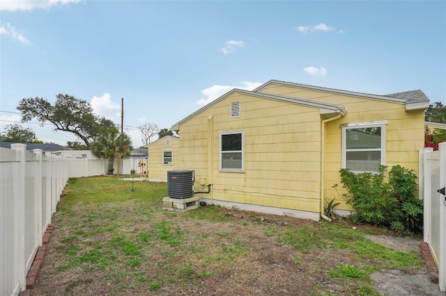 back of house featuring a yard and central AC