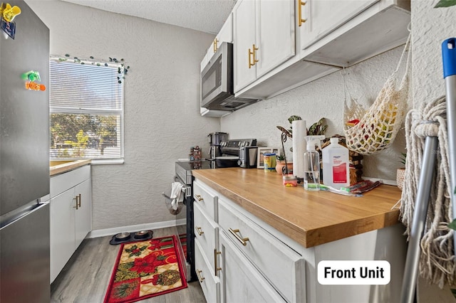 kitchen featuring a textured ceiling, light hardwood / wood-style floors, white cabinetry, and stainless steel appliances