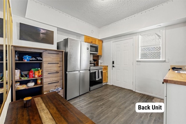 kitchen with wood-type flooring, a textured ceiling, and appliances with stainless steel finishes