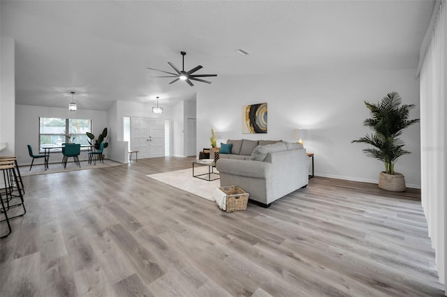 living room with ceiling fan, light hardwood / wood-style floors, and lofted ceiling