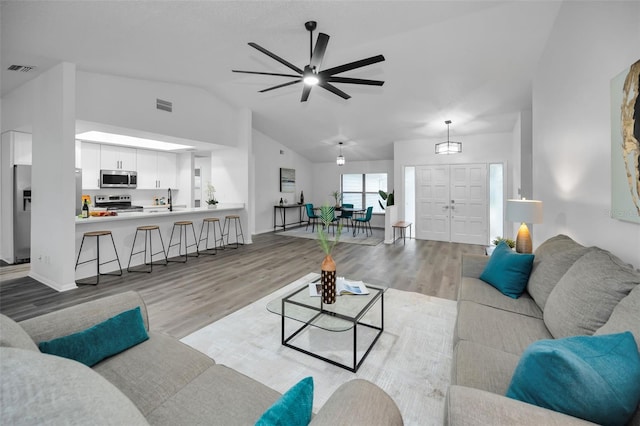 living room featuring ceiling fan, light wood-type flooring, and lofted ceiling