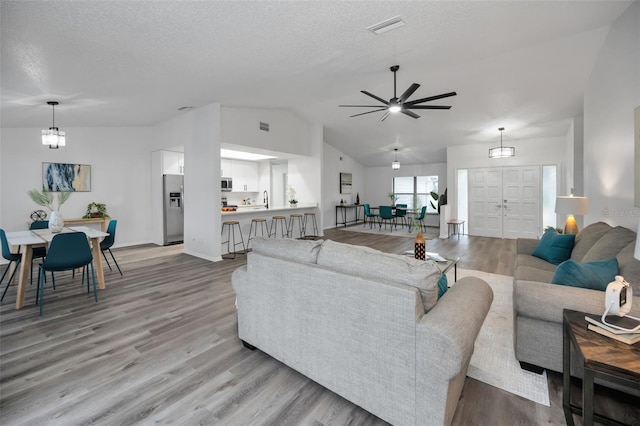 living room featuring ceiling fan, light hardwood / wood-style floors, and lofted ceiling