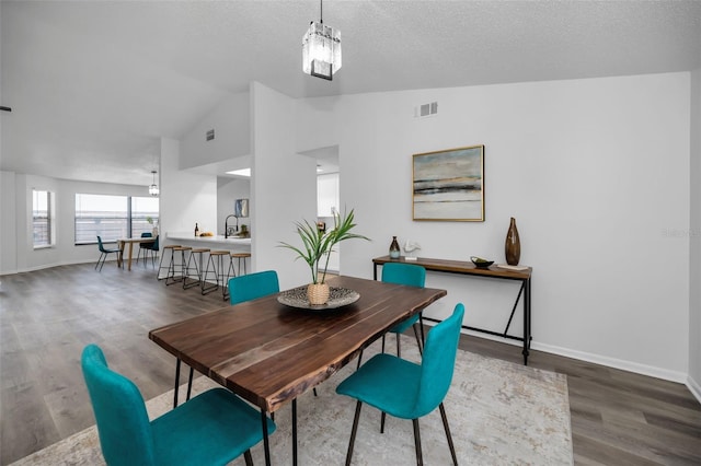 dining room featuring a textured ceiling, dark hardwood / wood-style floors, sink, and high vaulted ceiling