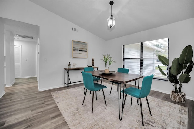 dining area featuring hardwood / wood-style floors and vaulted ceiling