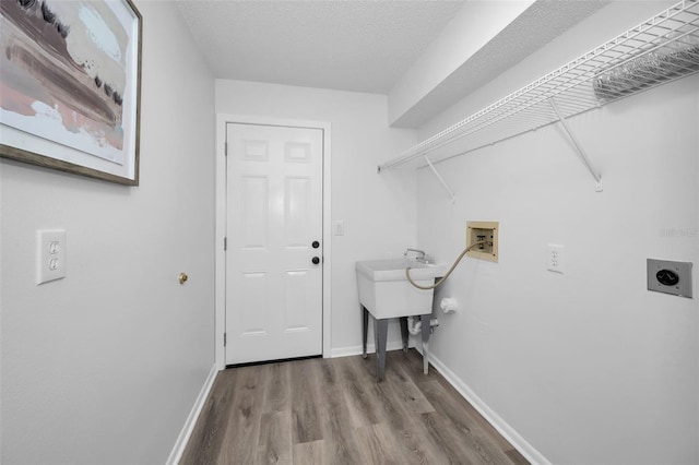 clothes washing area featuring electric dryer hookup, hookup for a washing machine, a textured ceiling, and hardwood / wood-style flooring