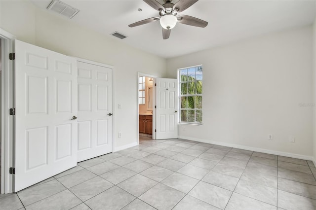 unfurnished bedroom featuring ceiling fan, light tile patterned floors, a closet, and ensuite bath