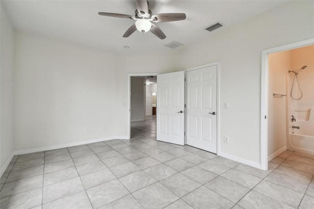 unfurnished bedroom with ceiling fan, light tile patterned floors, and ensuite bath