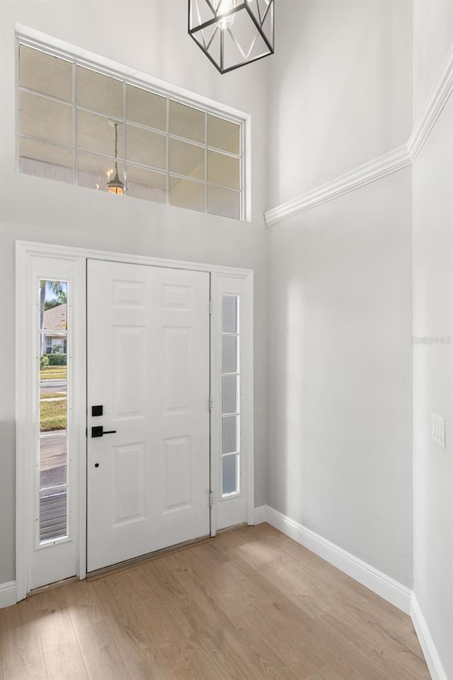 foyer entrance with a high ceiling, an inviting chandelier, and light hardwood / wood-style flooring