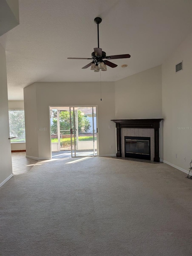 unfurnished living room with a tile fireplace, light carpet, ceiling fan, and lofted ceiling