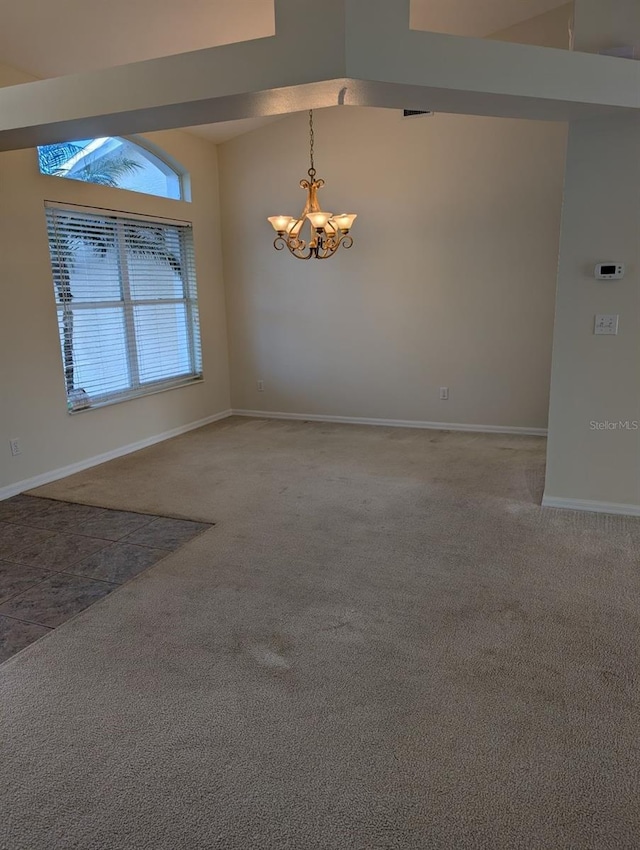 carpeted spare room featuring a notable chandelier