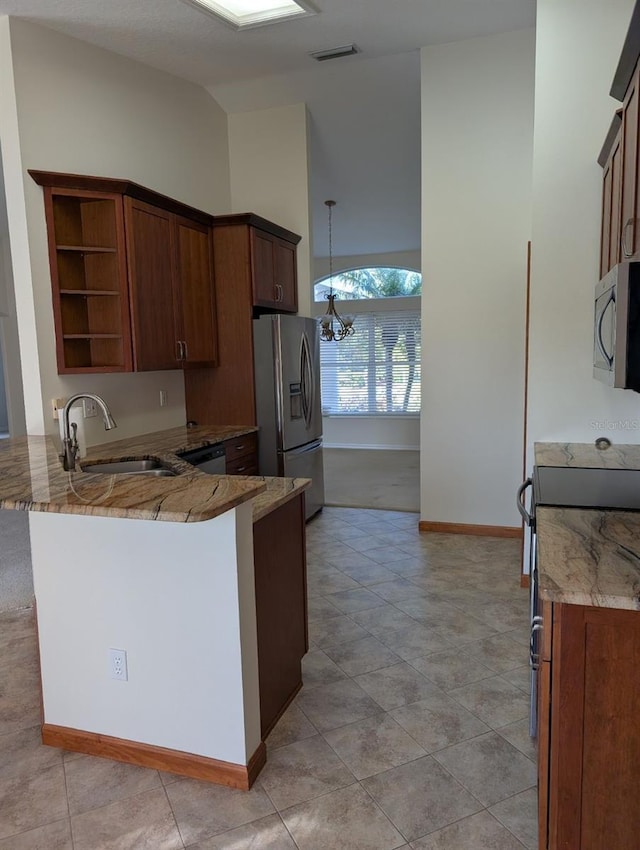 kitchen with kitchen peninsula, appliances with stainless steel finishes, light stone counters, sink, and a notable chandelier