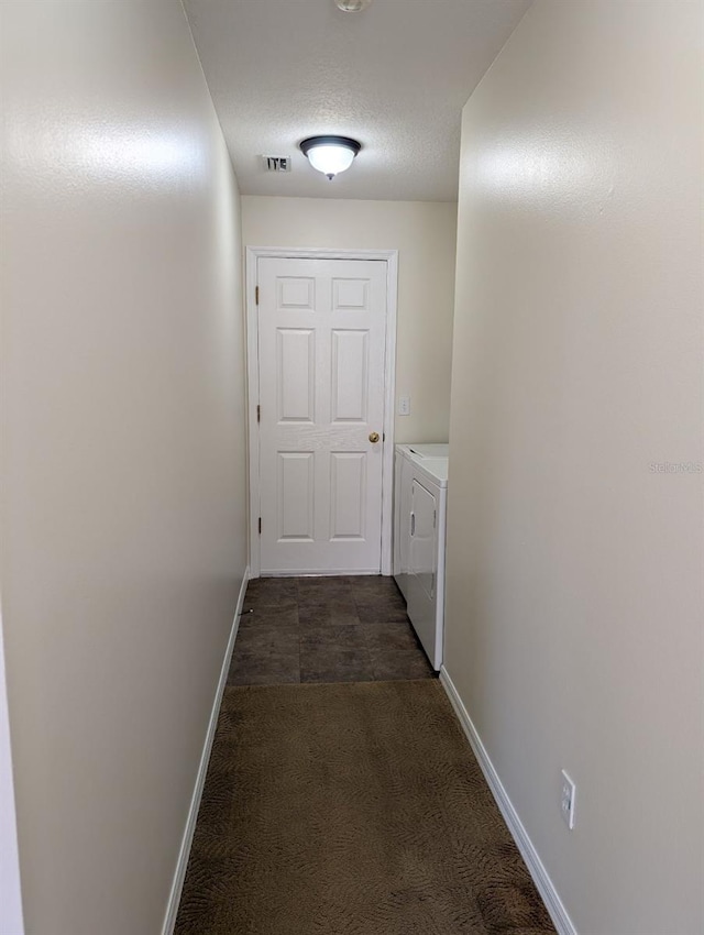 hall with washer and clothes dryer and a textured ceiling