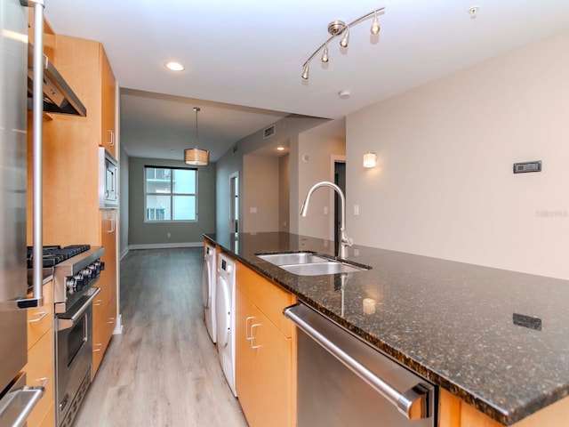 kitchen with a center island with sink, sink, light hardwood / wood-style flooring, appliances with stainless steel finishes, and decorative light fixtures