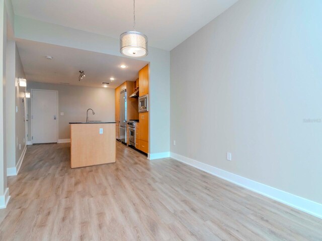 1120 E Kennedy Blvd Unit 927, Tampa, FL 33602 - kitchen featuring stainless steel appliances, dark countertops, light wood-type flooring, a kitchen island with sink, and open floor plan