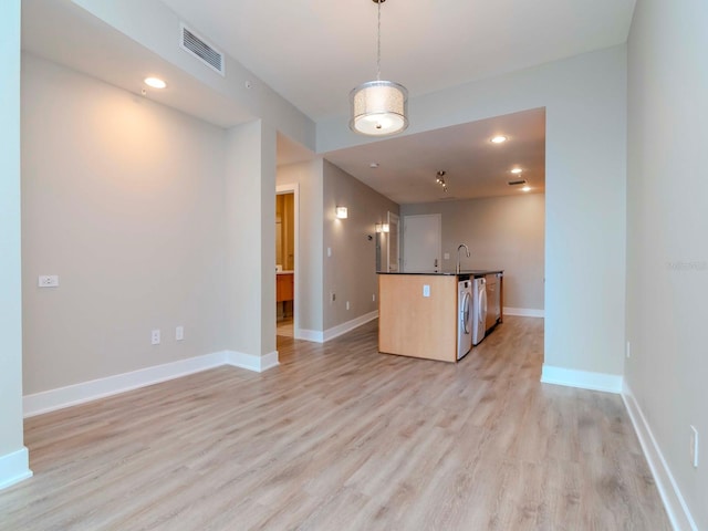 kitchen with decorative light fixtures, dishwasher, light wood-type flooring, and sink