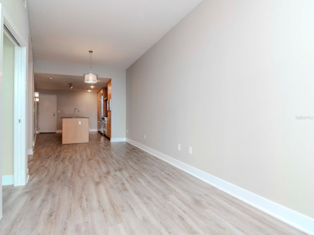 unfurnished living room featuring sink and light hardwood / wood-style floors