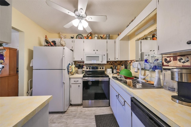 kitchen featuring a textured ceiling, white appliances, ceiling fan, sink, and white cabinetry