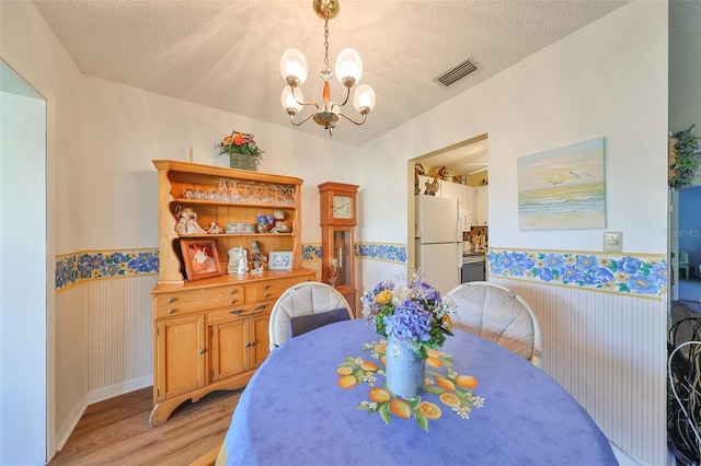 dining room featuring a chandelier, a textured ceiling, and light hardwood / wood-style floors