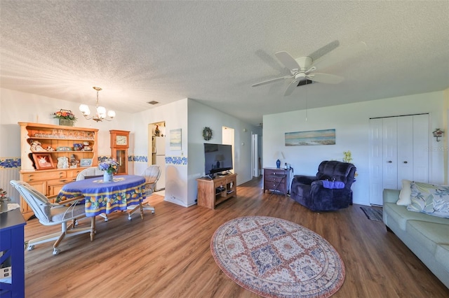 living room featuring ceiling fan with notable chandelier, dark wood-type flooring, and a textured ceiling