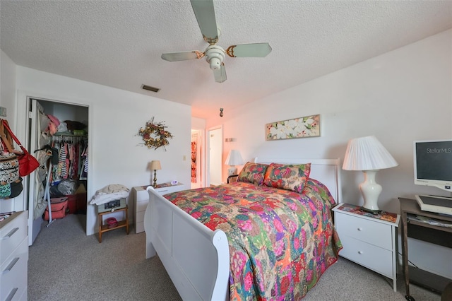 carpeted bedroom featuring ceiling fan, a closet, and a textured ceiling