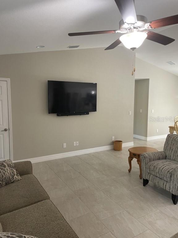 tiled living room featuring vaulted ceiling