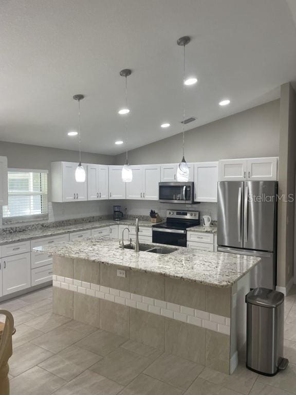 kitchen with decorative light fixtures, stainless steel appliances, lofted ceiling, and an island with sink