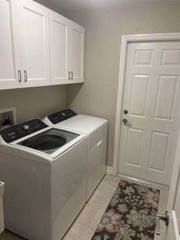 clothes washing area featuring cabinets and washing machine and clothes dryer