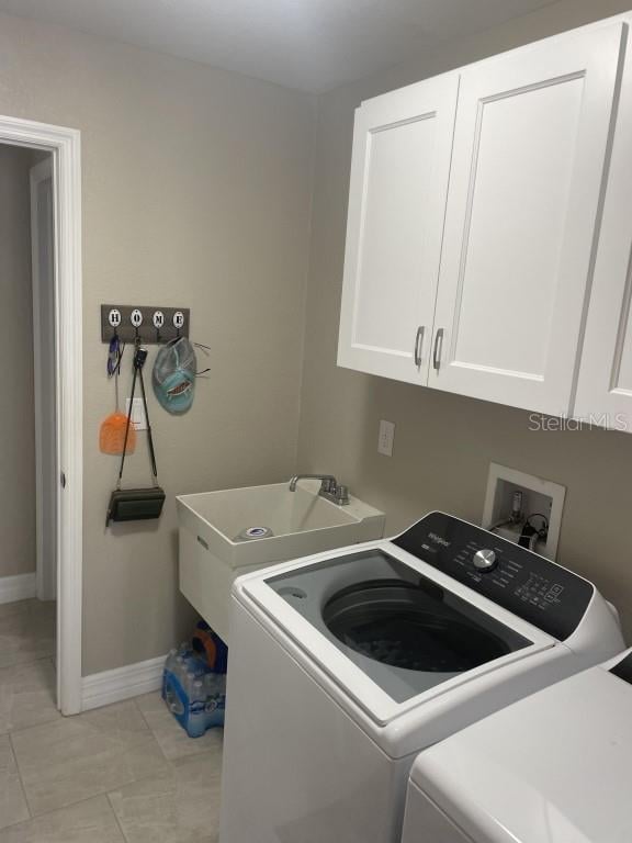 laundry area with washer and dryer, light tile patterned flooring, cabinets, and sink