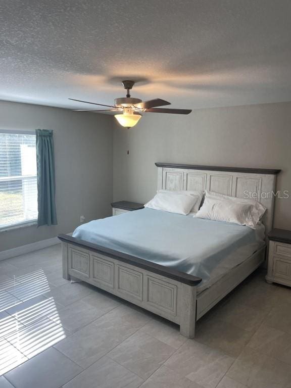 tiled bedroom featuring ceiling fan and a textured ceiling