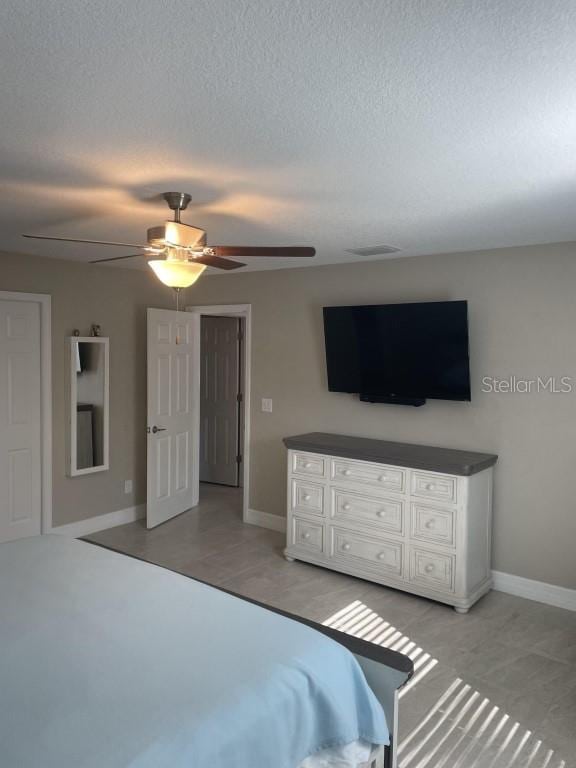 bedroom with ceiling fan and a textured ceiling