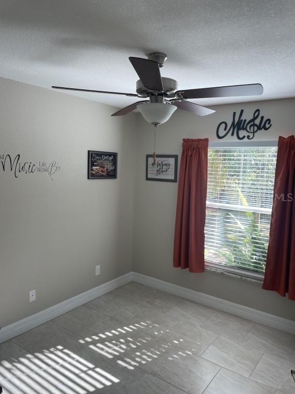 tiled spare room featuring ceiling fan and a textured ceiling