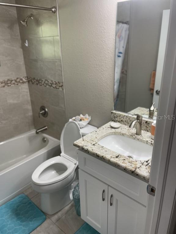 full bathroom with tile patterned flooring, vanity, toilet, and tiled shower / bath