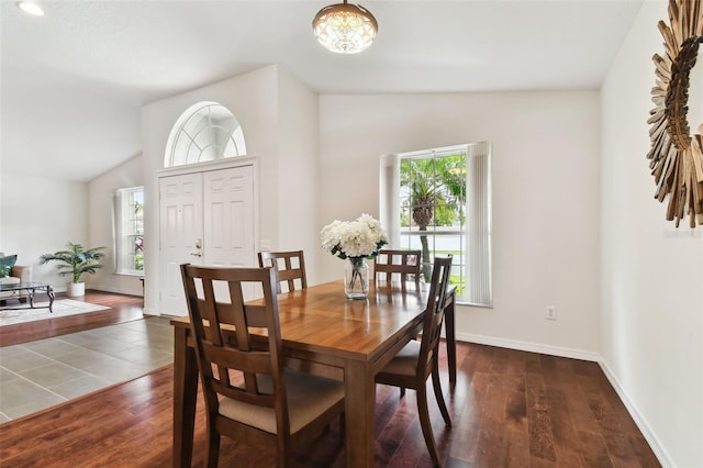 dining area featuring lofted ceiling, dark hardwood / wood-style flooring, and an inviting chandelier