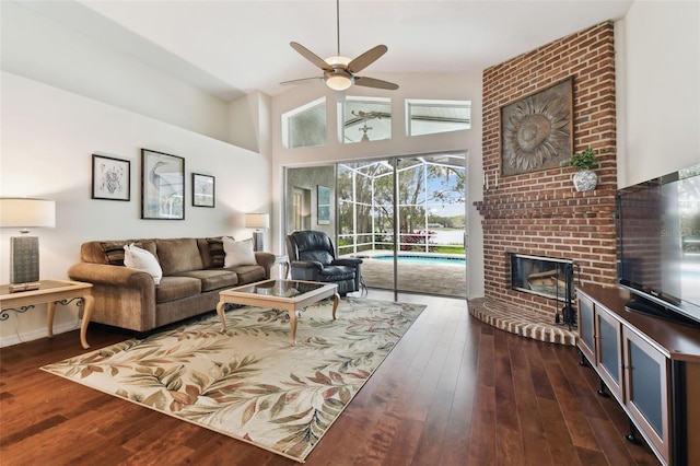 living room featuring ceiling fan, dark hardwood / wood-style floors, high vaulted ceiling, and a brick fireplace