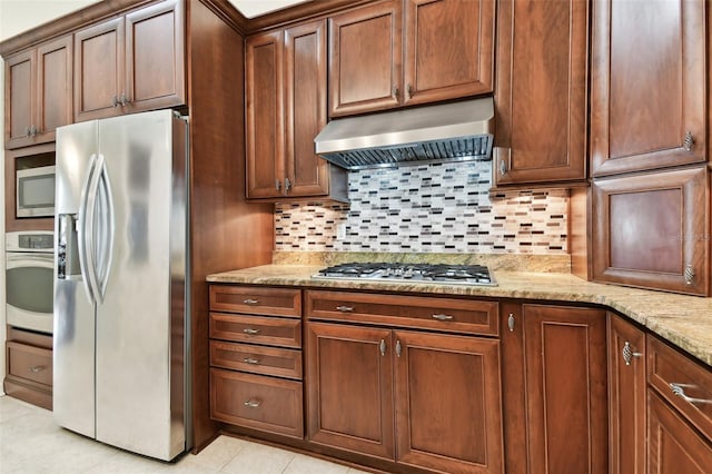 kitchen with light stone counters, tasteful backsplash, light tile patterned floors, stainless steel appliances, and exhaust hood