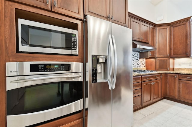 kitchen featuring appliances with stainless steel finishes, light stone counters, and decorative backsplash