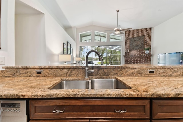 kitchen featuring light stone counters, lofted ceiling, dishwashing machine, and sink