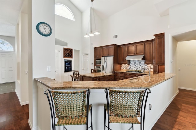 kitchen featuring dark hardwood / wood-style floors, decorative light fixtures, kitchen peninsula, and light stone countertops