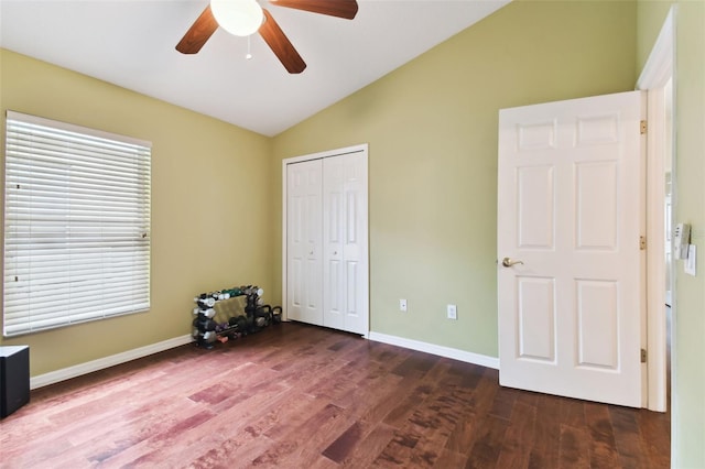 unfurnished bedroom featuring lofted ceiling, dark wood-type flooring, ceiling fan, and a closet