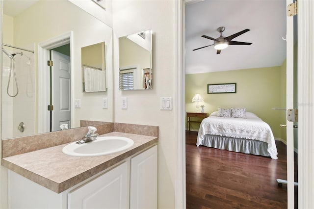 bathroom with a tile shower, vanity, hardwood / wood-style floors, and ceiling fan