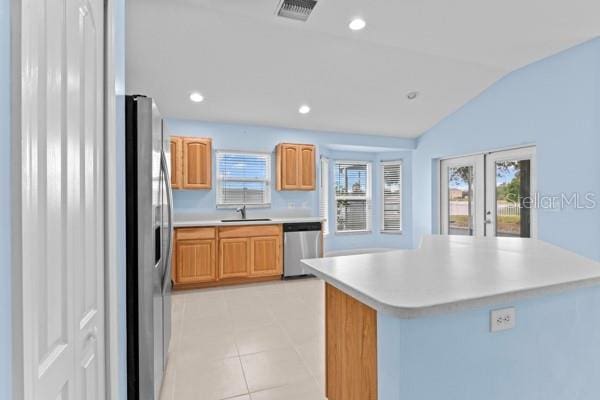 kitchen with stainless steel appliances, sink, a center island, lofted ceiling, and light tile patterned flooring