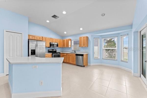 kitchen with sink, light tile patterned flooring, vaulted ceiling, a kitchen island, and appliances with stainless steel finishes