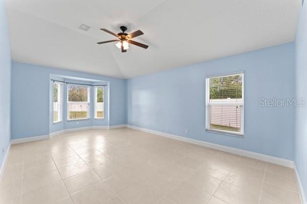 unfurnished room with ceiling fan, lofted ceiling, and light tile patterned flooring