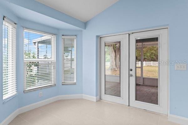 entryway featuring french doors, light tile patterned floors, vaulted ceiling, and a healthy amount of sunlight